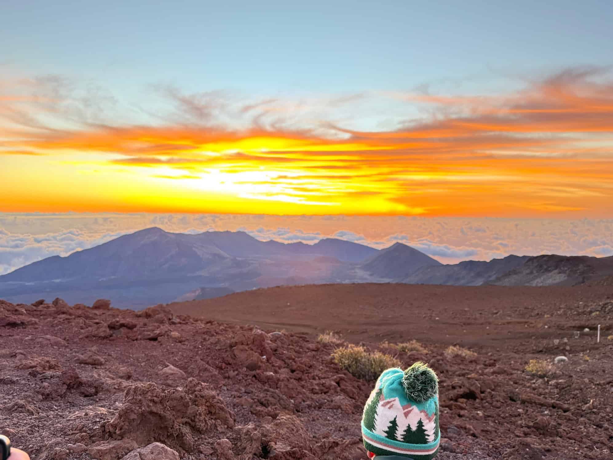 Boy watching the sun rise above the clouds at Haleakalā National Park Maui Hawaii